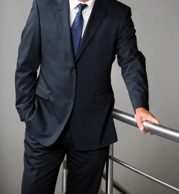 Cropped Head Man standing in a smart suit with hand one hand in pocket in an office