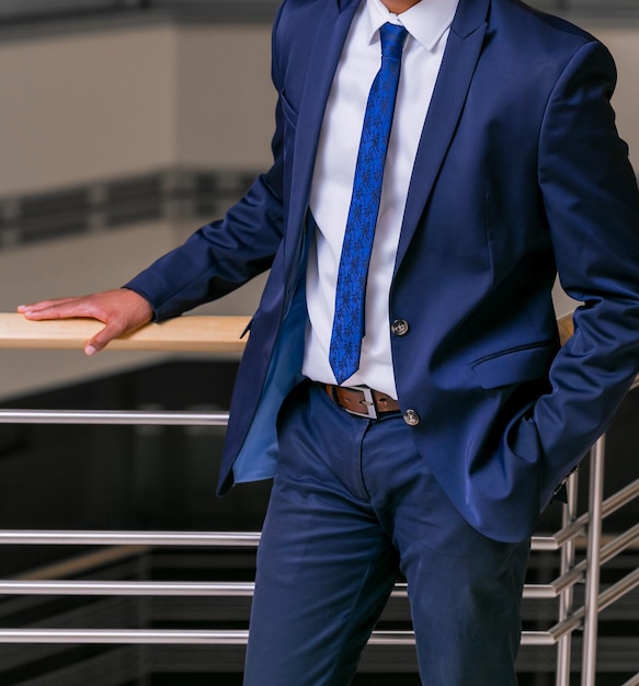 Cropped Head Man standing in a smart suit with hand one hand in pocket in an office