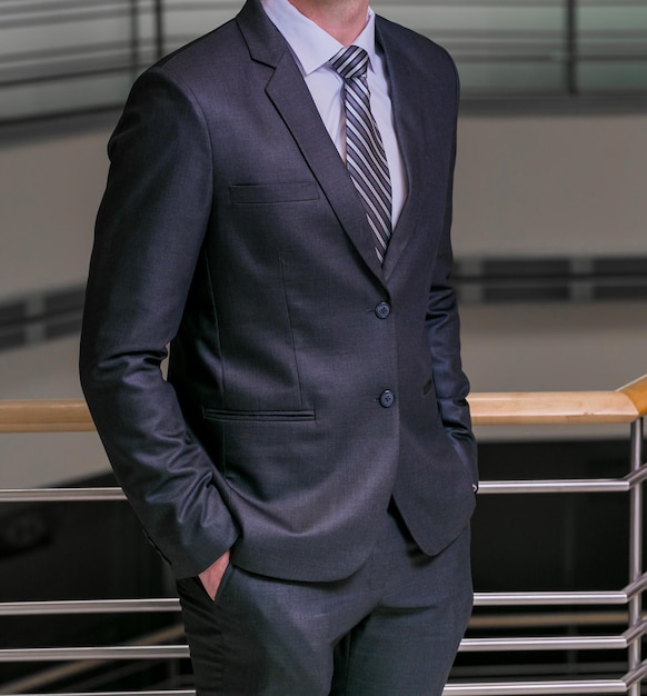 Cropped Head Man standing in a smart suit with hands in pockets in an office