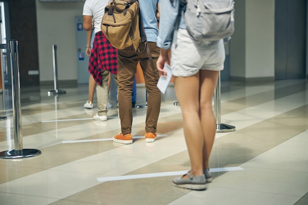 Cropped head portrait of international tourist group standing in line for passport control