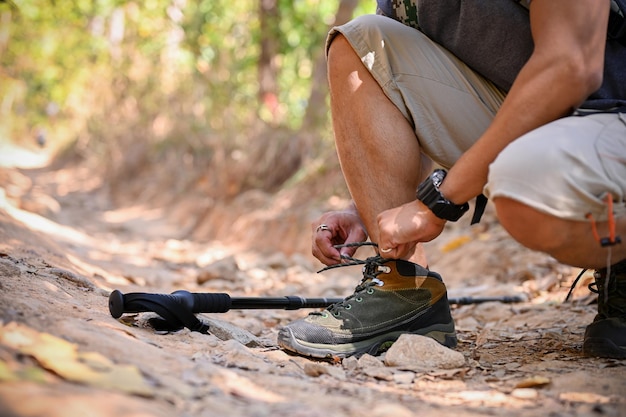 Cropped image of an active Asian man with trekking gear tying his shoelaces