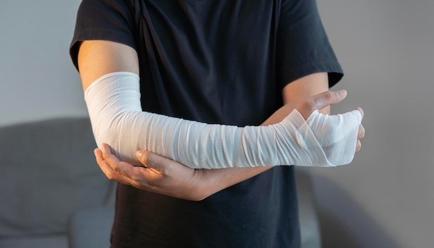 Cropped image of adult man with gauze bandage wrapped around his injured arms hand at home