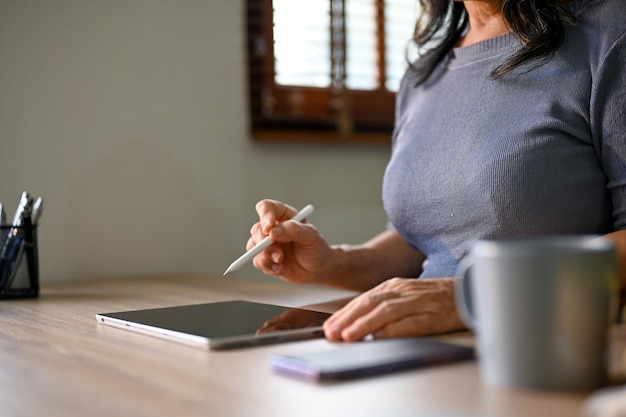 Cropped image of an Asianaged businesswoman using her digital tablet wit stylus pen