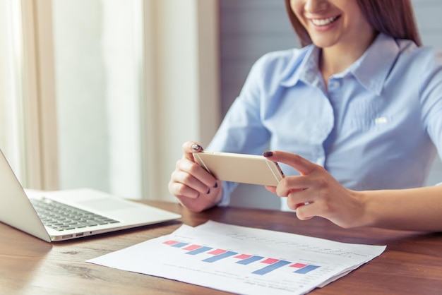 Cropped image of beautiful young business woman using a smartphone and smiling while working in office