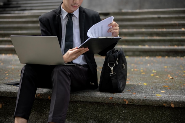 Cropped image of a businessman working remotely while sitting on stairs in front of the building