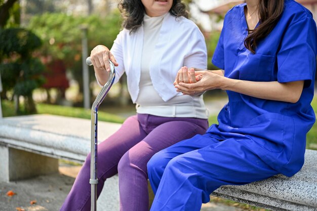 Cropped image of a caring Asian female nurse holding an old female patient's hand