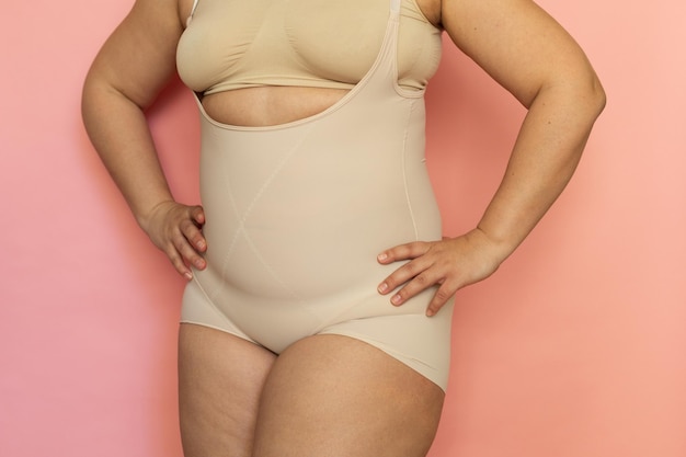 Cropped image of fat overweight woman in special fitness beige shape wear Fast gain weight with pregnancy Body health care Visceral obesity dehydrated dozed body Skin puffiness Close up