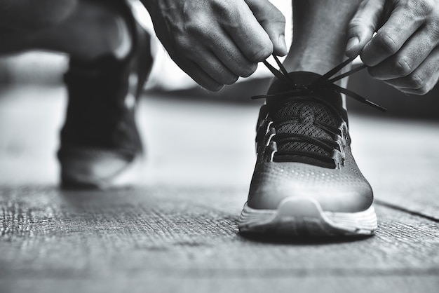 Cropped image of hands tying shoelaces on sneaker running surface background Hands of sportsman with pedometer tying shoelaces on sporty sneaker Running equipment concept