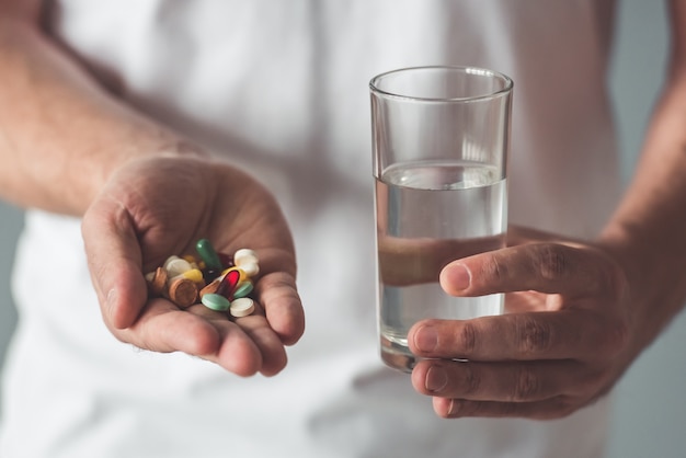 Cropped image of handsome man is holding a pill.