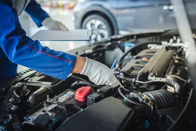 Cropped image of handsome mechanic in uniform is working in auto service. Car repair and maintenance.