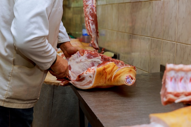 Cropped image of male butcher cutting raw meat with knife at counter in shop