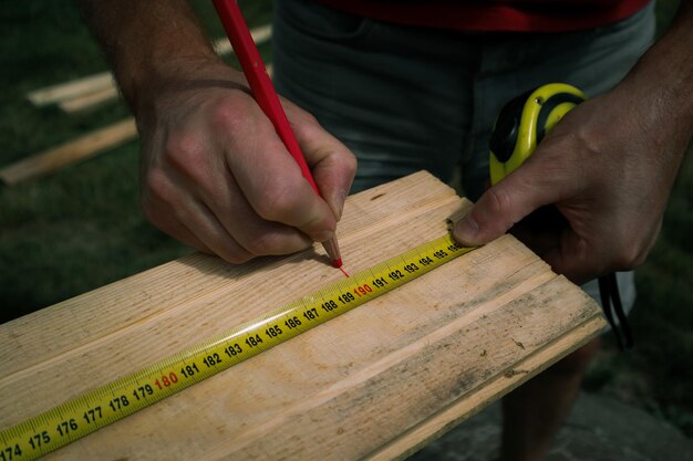 Photo cropped image of male carpenter marking on plank in workshop hands of a caucasian carpenter man in the workshop making some marks on the wood