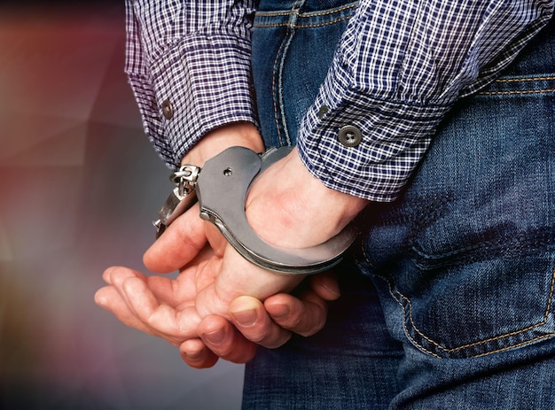 Cropped image of male hands in handcuffs behind his back