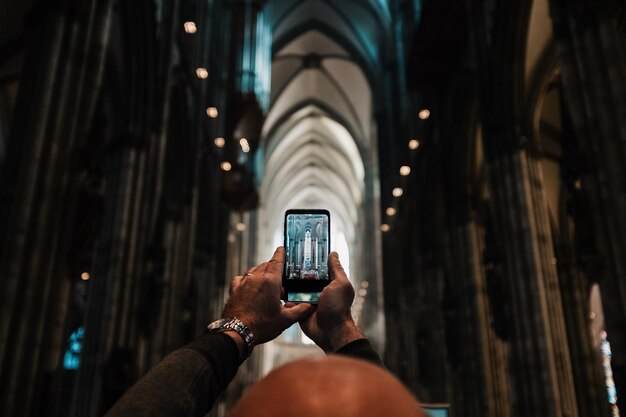 Photo cropped image of man photographing church with mobile phone