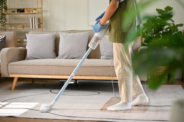 Cropped image of a man using stick vacuum cleaner to clean the carpet in living room