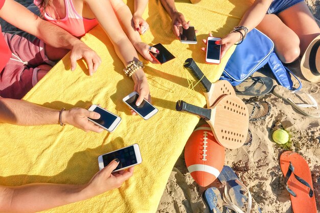 Photo cropped image of people using smart phone at beach