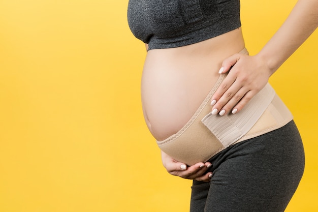 Cropped image of pregnancy belt dressed on suffering pregnant woman