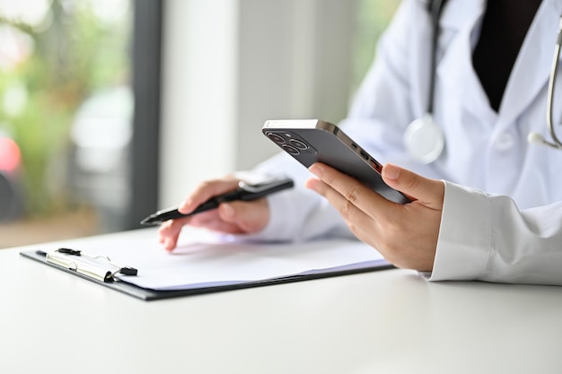 Cropped image of a professional Asian female doctor using her smartphone at her desk