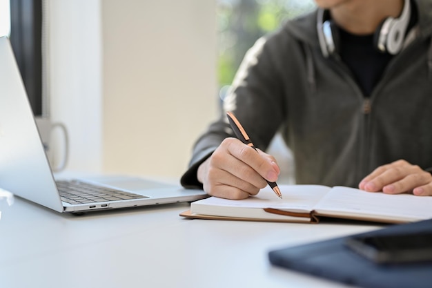 Cropped image Smart Asian male college student doing his school homework taking notes