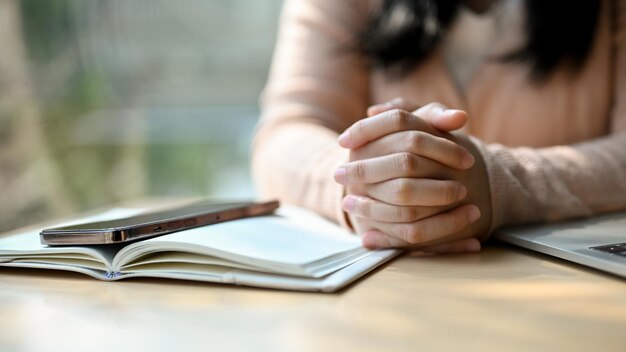 Cropped image A stressed young Asian female clasped her hands together on the table