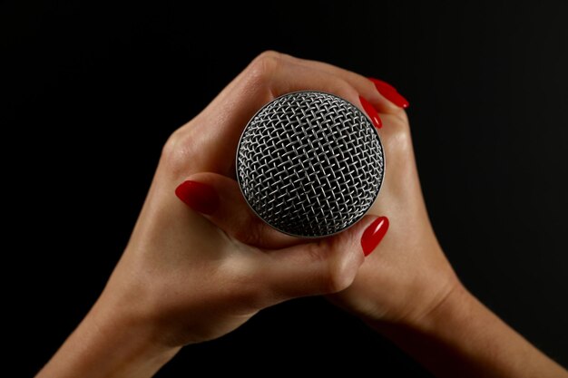 Cropped image of woman holding microphone over black background