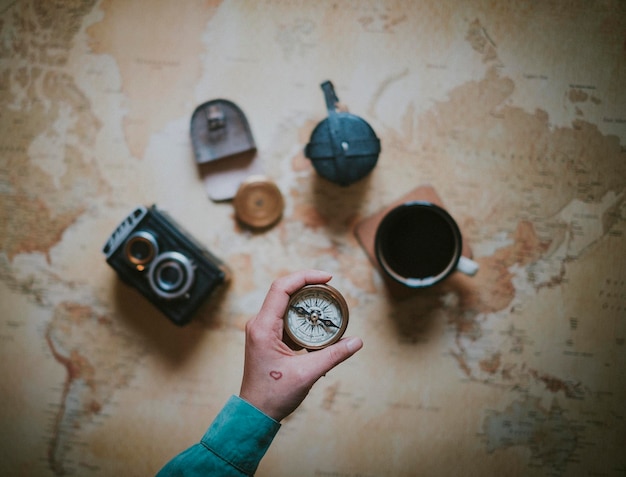 Photo cropped image of woman holding navigational compass over table