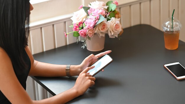 Cropped image of young beautiful woman's hands holding a cropped black smartphone