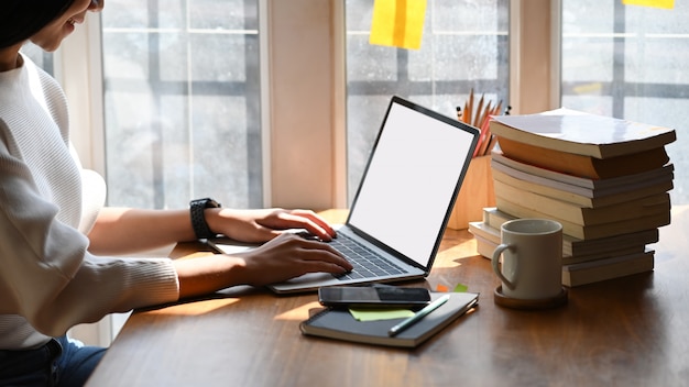 Cropped image of young beautiful woman working as writer typing on computer laptop with blank screen.