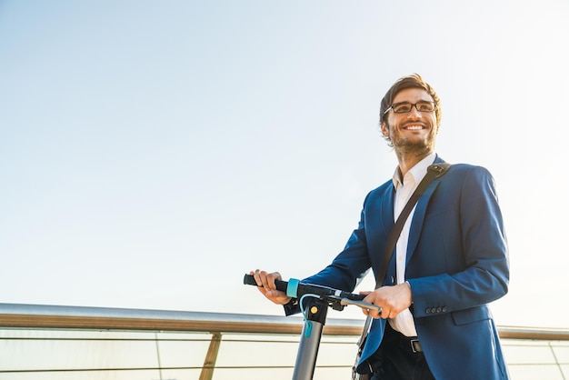 Cropped image of young business man in suit riding electric scooter