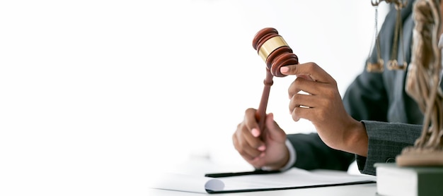 Cropped image of young female lawyer hands holding wooden judge gavel sitting at desk copy space panoramic background