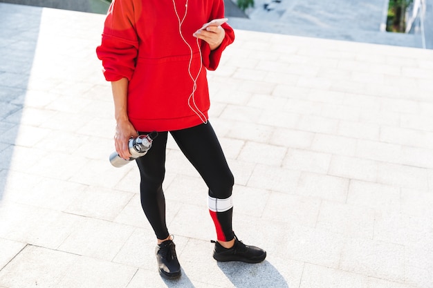 Cropped image of a young sportswoman listening to music with earphones, while resting after exercising