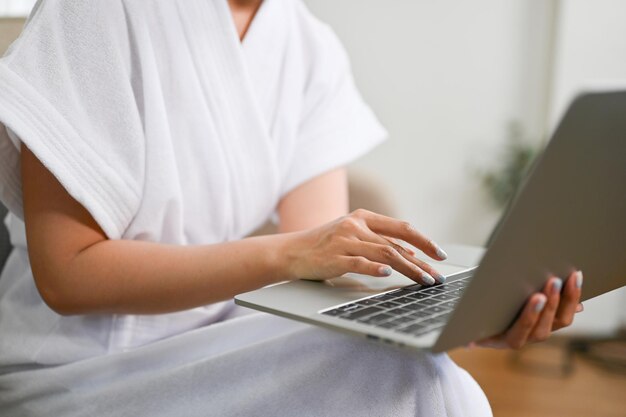 Cropped images A female in bathrobe using laptop typing on keyboard work from home