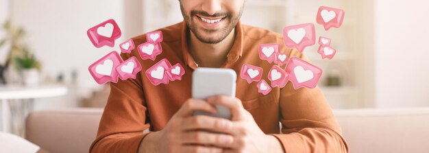 Photo cropped of man sits on a couch while checking his smartphone he is smiling broadly at the screen