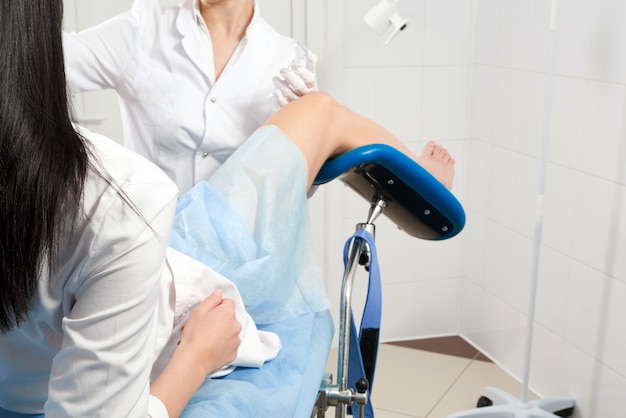 Cropped panorama of gynecologist examining a patient who is sitting in a gynecological chair. Female health concept.