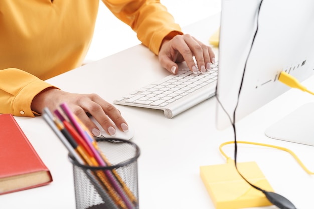 Cropped photo of european young businesswoman typing on computer while working in bright office