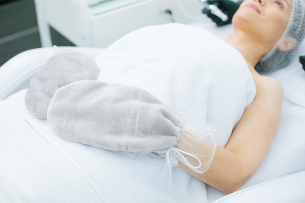 Cropped photo of lady undergoing warm and pleasant paraffin therapy