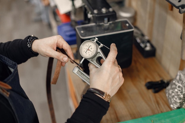 Cropped photo of mature craftsman's hands working in his workspace Man holding a special equipment There different stuff behind