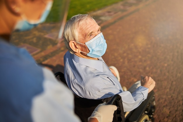 Cropped photo of a person rolling elderly in wheelchair