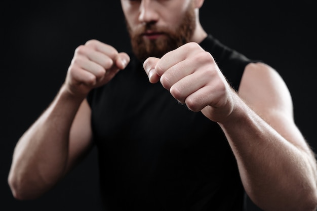 Cropped portrait of fighter isolated on dark wall