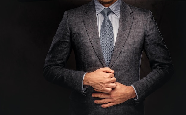 Cropped portrait of a successful businessman buttoning his elegant suit. Isolated on a dark background.