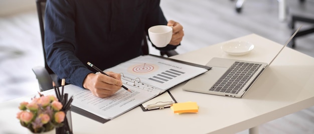 Cropped Professional male boss or businessman sipping coffee and working on paperwork in the office