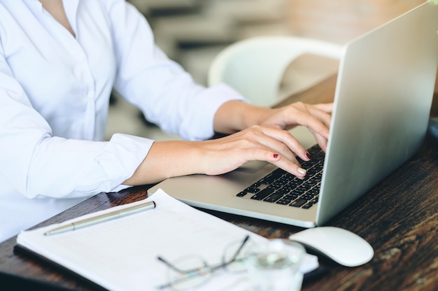 Cropped shot of businesswoman using laptop computer while sitting at office desk.