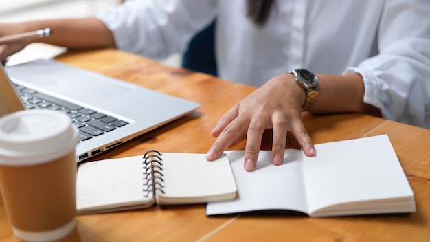 Cropped shot of businesswoman working on her project while using notebook in workspace