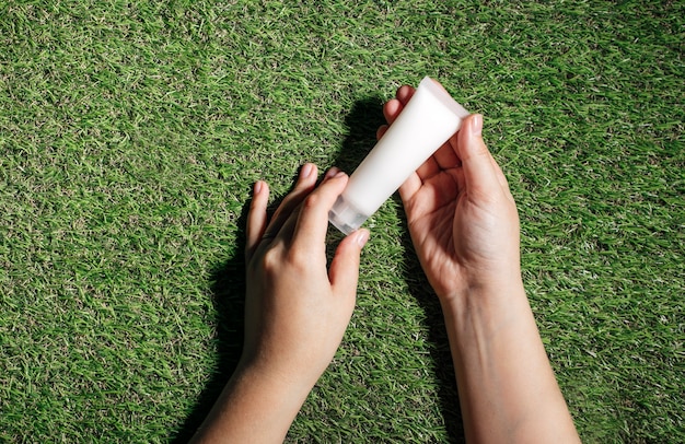 Photo cropped shot of hand holding bottle with serum lotion or essential oil on the grass