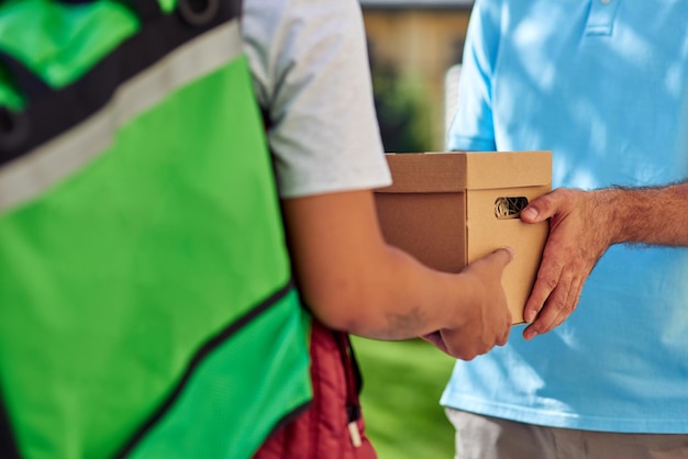 Cropped shot of a male courier with thermo bag delivering parcel to customer while standing