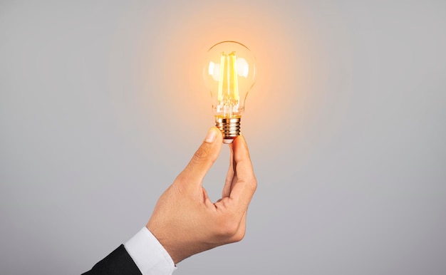 Cropped Shot Of Male Hand In Suit Holding Illuminated Light Bulb