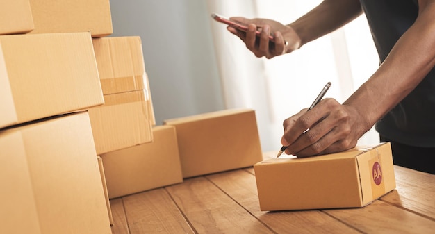 Cropped shot of man preparing a parcel for delivery at online selling business office.