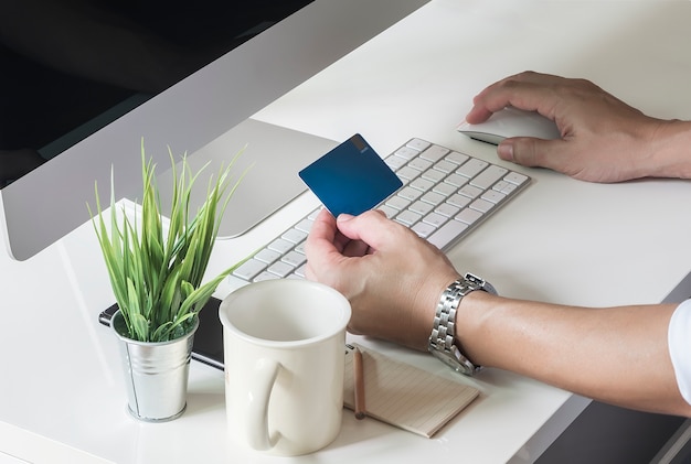 Cropped shot of man using destop computer and holding credit card to buying online