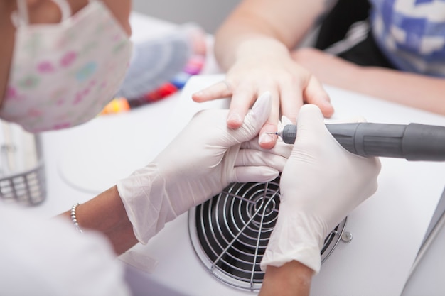 Cropped shot of manicurist removing cuticles with nail drill