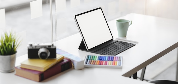 Cropped shot of modern graphic designer workplace with blank screen digital tablet, camera and office supplies